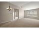 Bright, spacious living room with neutral carpeting, a chandelier, large window, and doorway at 7034 Pine Hollow Dr, Mount Dora, FL 32757