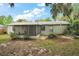 Rear exterior view featuring an enclosed screened patio, and mature landscaping at 706 Michigan St, Mount Dora, FL 32757
