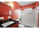 This bathroom features a shower-tub combo, black countertops, and orange walls at 706 Michigan St, Mount Dora, FL 32757