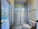 The bathroom features a glass-enclosed shower, toilet, and a window with blinds for natural light at 9018 Stinger Dr, Davenport, FL 33896