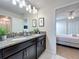 Bathroom with dual sinks, granite countertops, and a view of bedroom at 9018 Stinger Dr, Davenport, FL 33896