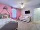 Bedroom featuring a bed, TV, pink walls, and a comfortable loveseat at 9018 Stinger Dr, Davenport, FL 33896
