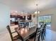 Elegant dining area with a dark wood table, seating for eight, and view of the kitchen and outdoor pool at 9018 Stinger Dr, Davenport, FL 33896