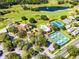 Wide aerial view of a well-manicured community with golf course, pool, tennis courts and clubhouse at 9089 Saint Andrews Way, Mount Dora, FL 32757