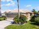 Inviting single-story home featuring a two-car garage, tile roof, stone accents, and lush landscaping at 9089 Saint Andrews Way, Mount Dora, FL 32757