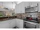 The kitchen features stainless steel appliances, tile backsplash, and white cabinets at 9089 Saint Andrews Way, Mount Dora, FL 32757