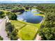Scenic aerial shot of pond with green space, golf course and putting greens at a property at 9089 Saint Andrews Way, Mount Dora, FL 32757