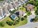 Overhead view showcases home, screened pool, palm trees and manicured lawn at 973 Baisley Trl, The Villages, FL 32162