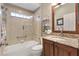 Well-lit bathroom with granite vanity, glass shower, and decorative shelving at 973 Baisley Trl, The Villages, FL 32162
