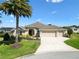 Beautiful single-story home with a three-car garage, lush landscaping, and a palm tree at 973 Baisley Trl, The Villages, FL 32162