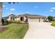 Well-maintained home featuring a circular driveway, beautiful lawn, and manicured garden beds at 973 Baisley Trl, The Villages, FL 32162