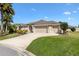 Charming home with a three-car garage, well-manicured lawn, and lush landscaping at 973 Baisley Trl, The Villages, FL 32162
