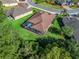 Aerial view of a well-maintained home featuring a screened-in pool, surrounded by a lush green lawn and mature trees at 10069 Lake Miona Way, Oxford, FL 34484