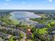 Aerial shot of a lakeside home in a residential area, showcasing its proximity to a large lake with vibrant vegetation at 10069 Lake Miona Way, Oxford, FL 34484