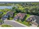 Aerial view of a beautifully landscaped home with a well-manicured lawn in a neighborhood near a lake and lush greenery at 10069 Lake Miona Way, Oxford, FL 34484
