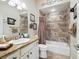 This bathroom features a tiled shower/tub with decorative accents, vanity with storage, and neutral color palette at 10069 Lake Miona Way, Oxford, FL 34484