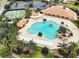 Aerial view of a large community pool with lush landscaping and various amenities including tennis courts at 10069 Lake Miona Way, Oxford, FL 34484