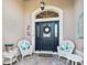 Welcoming front door featuring decorative wreath, potted plants, and cozy seating arrangement on a brick porch at 10069 Lake Miona Way, Oxford, FL 34484