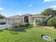 Inviting one-story home showcasing lush landscaping, brick paved driveway, and a cozy, well-lit entryway at 10069 Lake Miona Way, Oxford, FL 34484