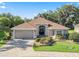 Charming one-story home with a well-manicured lawn, brick paved driveway, and a welcoming entrance at 10069 Lake Miona Way, Oxford, FL 34484