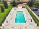 Aerial view of a pool with lounge chairs, umbrellas, and a nearby pavilion for a resort-like experience at 10069 Lake Miona Way, Oxford, FL 34484
