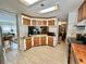 Well-lit kitchen boasts warm wood cabinets, neutral countertops, and tiled floors at 104 Valencia Cv, Leesburg, FL 34748