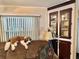 Cozy living room detail showcasing a stuffed animal on a sofa, a window with blinds, and a cabinet with glass doors at 104 Valencia Cv, Leesburg, FL 34748