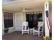 A relaxing outdoor patio with white rocking chairs, ceiling fan, and a beautiful view, perfect for enjoying tranquil moments at 106 Baytree Blvd, Tavares, FL 32778