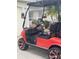 Side view of a red golf cart with black interior, custom wheels, and a clear windshield at 106 Baytree Blvd, Tavares, FL 32778
