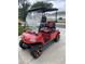 Custom red golf cart featuring black and red seats and sporty wheels parked on a driveway at 106 Baytree Blvd, Tavares, FL 32778