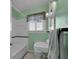 Bathroom with a bathtub and shower featuring mint green walls and a large window at 1109 W Line St, Leesburg, FL 34748