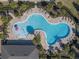 An aerial view of the community pool and splashpad area surrounded by lounge chairs and lush landscaping at 1128 Cavender Creek Rd, Minneola, FL 34715