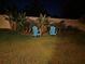 Backyard at night featuring Adirondack chairs surrounded by lush greenery and landscape lighting at 1128 Cavender Creek Rd, Minneola, FL 34715