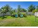 Green backyard with vibrant palm trees, lawn, white fence, and inviting Adirondack chairs at 1128 Cavender Creek Rd, Minneola, FL 34715