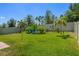 Large backyard with a well-maintained lawn, tropical plants, and comfortable Adirondack chairs at 1128 Cavender Creek Rd, Minneola, FL 34715