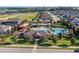 View of neighborhood pool with surrounding homes, green space, playground, parking lot and trees under bright sky at 1128 Cavender Creek Rd, Minneola, FL 34715