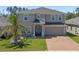 Charming two-story home featuring a well-manicured lawn, brick driveway, and welcoming front entrance at 1128 Cavender Creek Rd, Minneola, FL 34715
