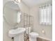 Powder room with pedestal sink, decorative mirror, and neutral color palette at 1281 Gatewood Ave, Minneola, FL 34715