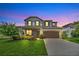 Charming two-story home with lush landscaping, brick accents, and a spacious two-car garage at dusk at 1281 Gatewood Ave, Minneola, FL 34715