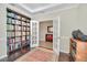 Bright office with a large bookshelf, double doors, and a view into the hallway, styled with a patterned rug at 1281 Gatewood Ave, Minneola, FL 34715