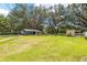 Expansive green backyard featuring mature trees and versatile outbuildings, perfect for outdoor activities at 13050 Se 120Th St, Ocklawaha, FL 32179