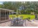 A brick patio includes seating, an umbrella, grill, and an adjacent screened-in hot tub and large yard at 13050 Se 120Th St, Ocklawaha, FL 32179