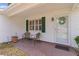 Close-up view of a cozy front porch with two chairs and a nicely decorated door and welcome wreath at 1358 E Schwartz Blvd, The Villages, FL 32159