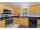 Kitchen with black countertops, stainless steel appliances, and light wooden cabinets at 1358 E Schwartz Blvd, The Villages, FL 32159