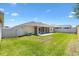 An expansive backyard featuring a screened-in patio, bordered by fencing on a sunny day at 1409 Gatlin Pl, The Villages, FL 32163