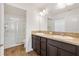 Bright bathroom featuring double sink vanity, wood-look flooring, and walk-in shower at 1409 Gatlin Pl, The Villages, FL 32163