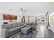Bright, open living room features modern gray sectional sofa, ottoman and view to kitchen with large island at 15287 Aquarius Way, Mascotte, FL 34753