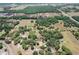 Wide aerial shot of vast land with scattered trees, a small building and a house in the bottom-center at 155 W C-466, Lot # 1 W C 466, Oxford, FL 34484