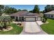Beautiful home with a three-car garage, manicured lawn, and patterned driveway at 17194 Se 85Th Willowick Cir, The Villages, FL 32162