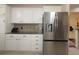 Modern kitchen featuring a stainless steel refrigerator, white cabinetry, and granite countertops at 17194 Se 85Th Willowick Cir, The Villages, FL 32162